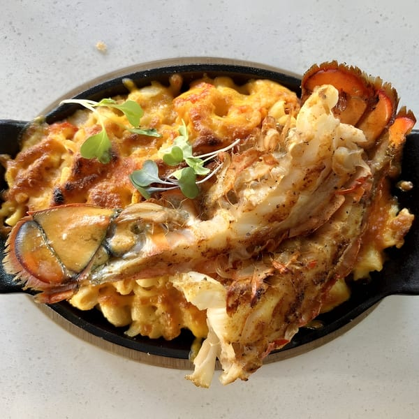 Just Brunch's lobster mac and cheese, a skillet of cheesy pasta topped with a whole lobster tail.