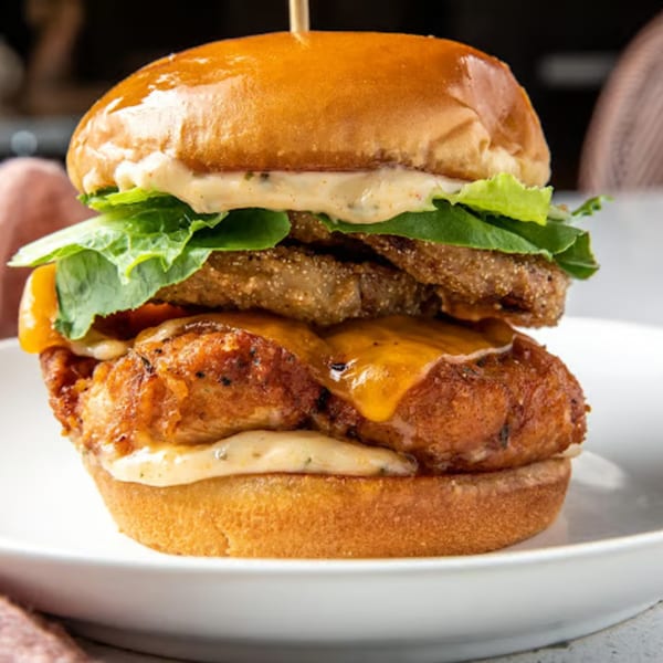 Just Brunch's fried chicken sandwich with melted cheese, lettuce, and sauce on a brioche bun.