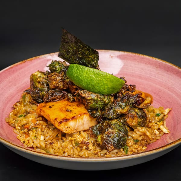 Just Brunch's salmon and crispy Brussels sprouts over fried rice, garnished with lime and nori.